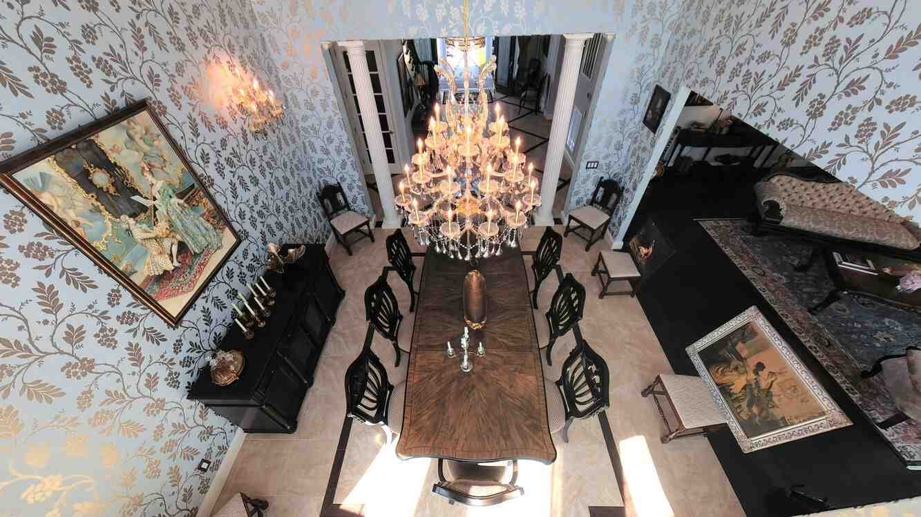 Formal dining room with set table beneath a chandelier
