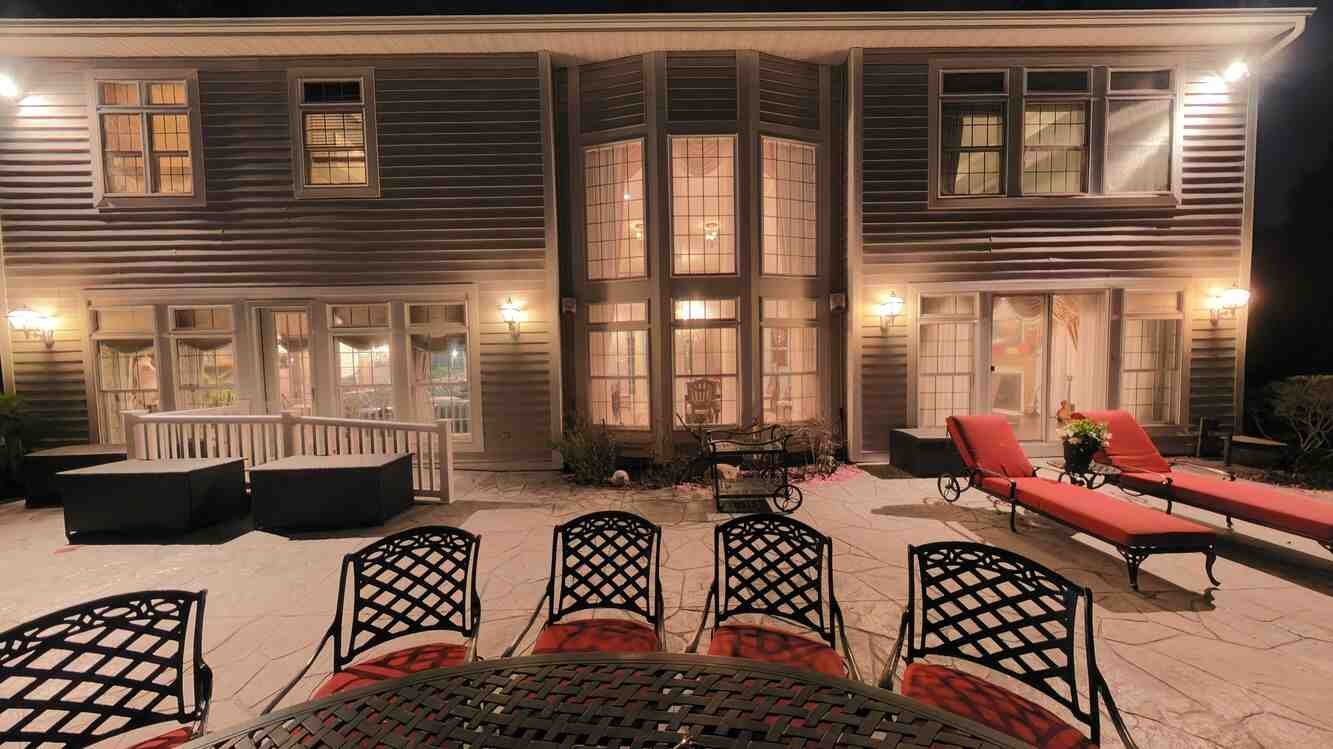Rear of the home at night showing the terrace and outdoor kitchen lit against the pond
