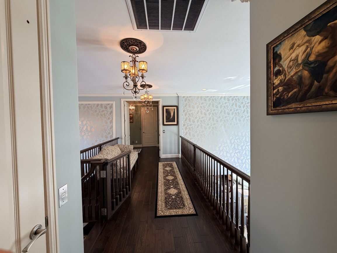 Second-floor hallway with hardwood floors, runner, and the door to the residential elevator